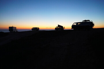 silhouette of camper vans parking on cliff during sunset  