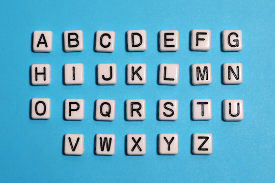 English alphabet. Beads white tiles on a blue background.