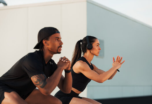 Two athletes are doing sit-ups on a rooftop. Fitness couple exercising together.