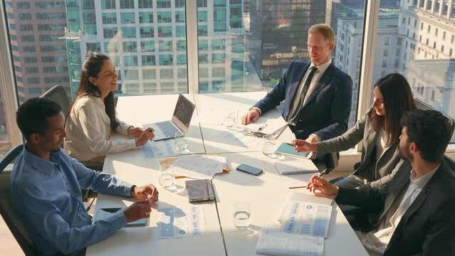 Multiethnic professional busy employees and executives board team people at group meeting discussing work results managing company project plan working together in modern board room office.