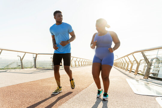 Portrait of happy Nigerian man and woman running together outdoors