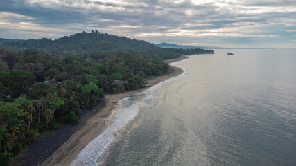 Drone view of beautiful jungle caribbean beach with nice surf close to Playa Cocles and Puerto Viejo in Costa rica. View towards the trees. hazy sea and spray.