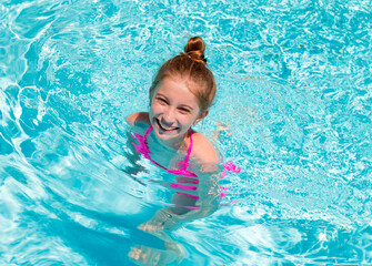 Fototapeta na wymiar Teen girl in swimming pool squinting her eyes