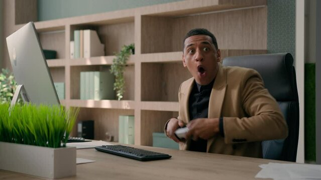 Funny African American office worker employee businessman playing online video game on computer take break fun entertainment humor male lazy business man fooling hide joystick pretend working smiling
