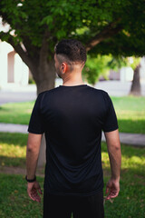 Hombre de espaldas entrenando con playera negra en el parque 