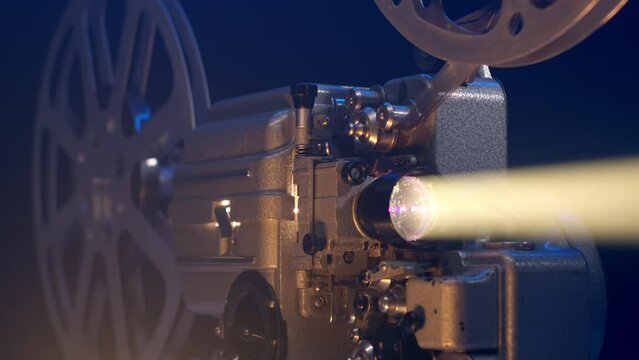 Close up view of old vintage movie projector playing film and camera move around it. 16mm retro projector. The concept of old film or cinema. beam of light illuminates in dark.