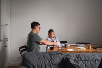 Father and child girl doing origami crafts together. Modern parenthood, weekend education activities at home of parents with children. 