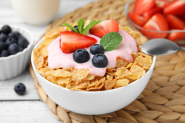 Delicious crispy cornflakes, yogurt and fresh berries in bowl on white table, closeup. Healthy breakfast