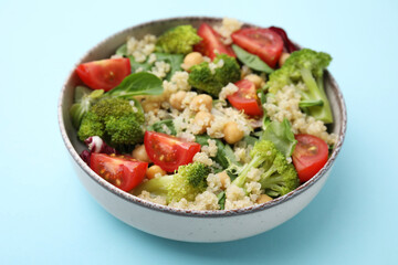 Healthy meal. Tasty salad with quinoa, chickpeas and vegetables on light blue table, closeup