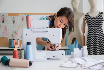 Confidence female dressmaker with a sewing machine in her tailor shop.