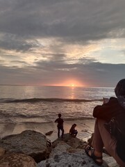 happy people with sunset in the sea under cloudy sky