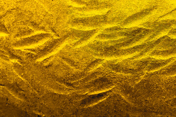 Rough gold colored metal surface with a engraved wave pattern texture.