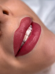 permanent makeup on the lips of a young woman of a delicate peach shade close-up, a girl after a cosmetic procedure with smooth and clean healthy skin.