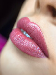 permanent makeup on the lips of a young woman of a delicate peach shade close-up, a girl after a...