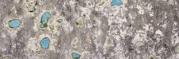 Peeling paint on the wall. Panorama of a concrete wall with old cracked flaking paint. Weathered rough painted surface with patterns of cracks and peeling. Wide panoramic texture for design background