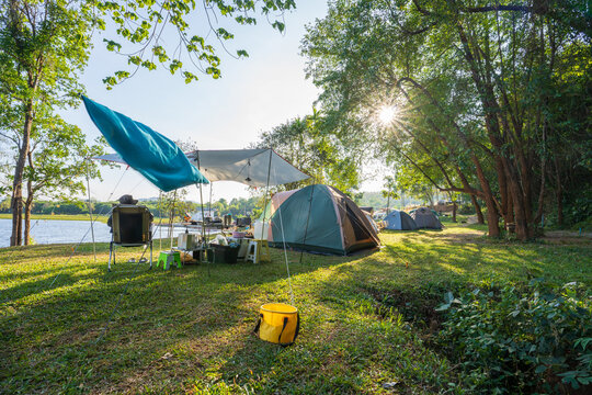 Outdoor camping tent with tarp or flysheet on green grass and light morning, vacation picnic on holiday relax near lake, Tourism concept.