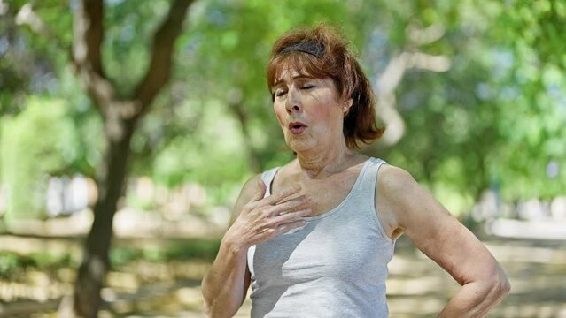 Middle age woman wearing sportswear sweating at park