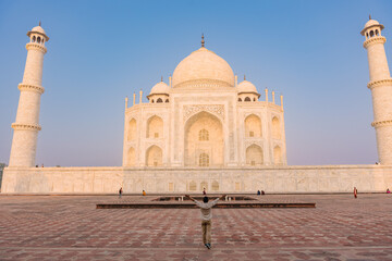 The man with arms around his back standing in front of Taj Mahal indian palace. Islam architecture. 