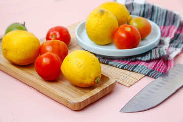 Fresh lemons and tomato and a slicing knife