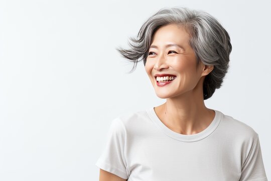 Close-up portrait of a stylish beautiful Asian woman in her 50s. Skin care concept. Luxurious middle-aged woman with a short gray hair looking at copy space.
