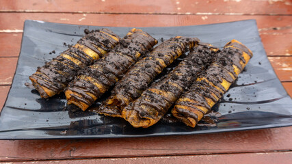 Fried banana rolls on plate. Fried crisp banana with melted chocolate served for snack.