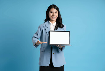 Fototapeta premium image of young businesswoman using laptop on blue background