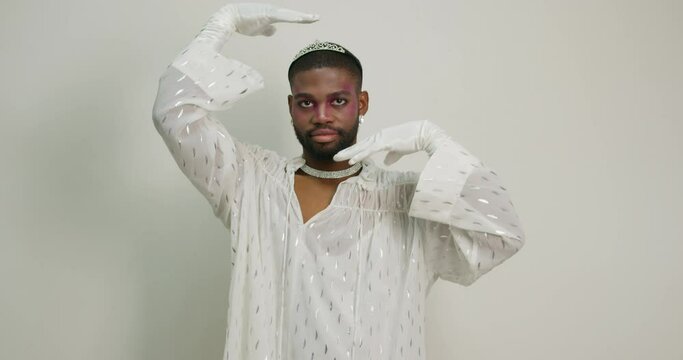 Black guy with makeup in stylish white outfit and gloves in dancing Handsome transgender man has fun Diversity of a person as person. costume for LGBT Gay performs in studio entertainment Magic dance