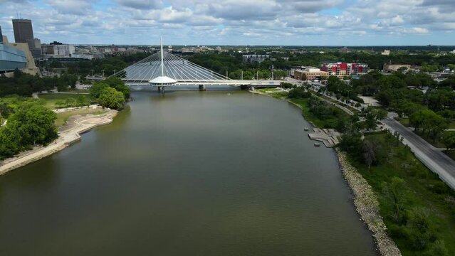 Aerial shot drone flies over the Red River toward the Esplanade Riel Footbridge in downtown Winnipeg, Canada