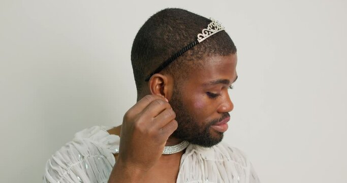 young black bearded transgender takes of earrings, crown from head wipes cosmetics from face close up portrait Slow motion Actor going to bed after working day, performance