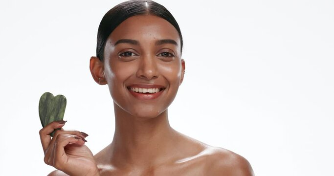 Gua sha, natural beauty or woman with cosmetics, face or luxury isolated on a white studio background. Person, portrait or model with rose quartz, shine or wellness with skincare, glow or dermatology