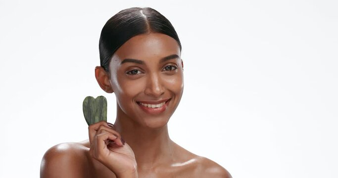 Gua sha, face and woman with skincare, beauty and cosmetics isolated on a white studio background. Portrait, person and model with rose quartz, shine and wellness with dermatology, glow and wellness