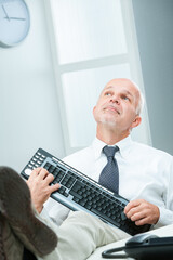 Fototapeta premium Businessman mimics guitar, uses keyboard, daydreams