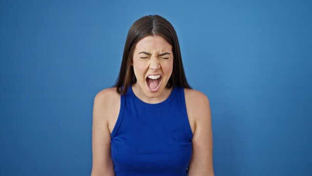 Young beautiful hispanic woman screaming loudly over isolated blue background
