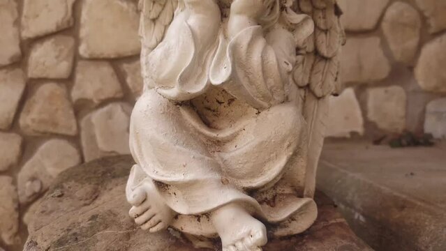 Stone statuette of an angel in the park in summer.