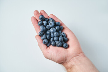 blueberry in hand on white. Male hand
