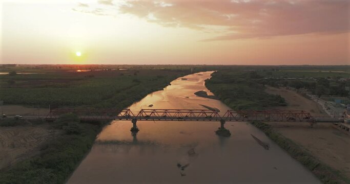 Aerial shot of Tumbes river, bridge and city at sunset. Tropical city at north of Per&uacute;. 