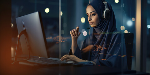 Arabic business woman with handset working on computer at office.