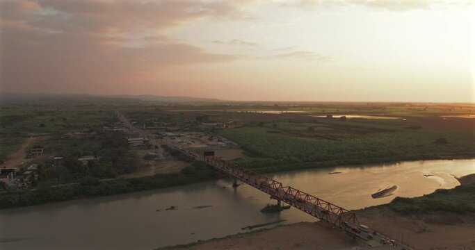 Aerial shot of Tumbes river, bridge and city at sunset. Tropical city at north of Per&uacute;. 