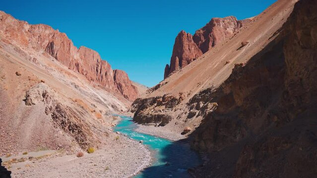 4K shot of the blue Tsarap River flowing between Himalayan mountains in Zanskar Valley in Ladakh, India. Clear blue water of the river on the way towards the Phuktar gompa. Nature Landscape. 