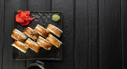 Delicious sushi rolls with eel on a black stone plate, top view. Traditional Japanese food.