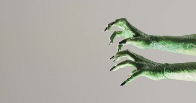 Video of halloween green monster hands with copy space on grey background
