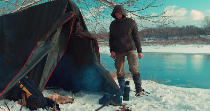 backpacker stays on bank of river he puts up a tent on a sunny spring day Slow motion adventure Extreme rest, holiday Active lifestyle Winter survival concept. bushcraft