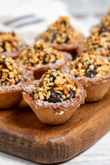 Tart cookies. Delicious mini tartlets with chocolate cream and nuts on a white background