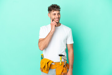 Young electrician blonde man isolated on green background thinking an idea while looking up