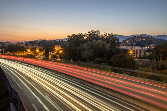 Photo à l'heure bleue en pose longue avec les filets des lumières des voitures sur l'autoroute A8 près de Nice au pied du château Grimaldi de Cagnes sur Mer sur la Côte d'Azur