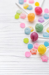 Fototapeta na wymiar Sweet lollipops and candies on white wooden background