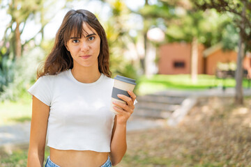 Young woman holding a take away coffee at outdoors with sad expression