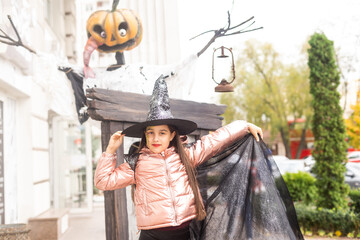 Obraz na płótnie Canvas teenage girl in witch hat plays in the park, child plays wizard, costume for halloween concept