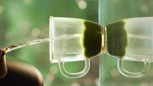 Matcha green tea preparation process. Pours organic matcha green tea powder into a cup with a spoon. Mixing matcha tea with whisk. Healthy matcha drink. Vertical video