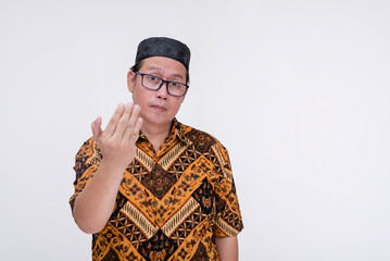 An irked man challenges someone after being insulted by their comments. Wearing a batik shirt and songkok skull cap. Isolated on a white background.